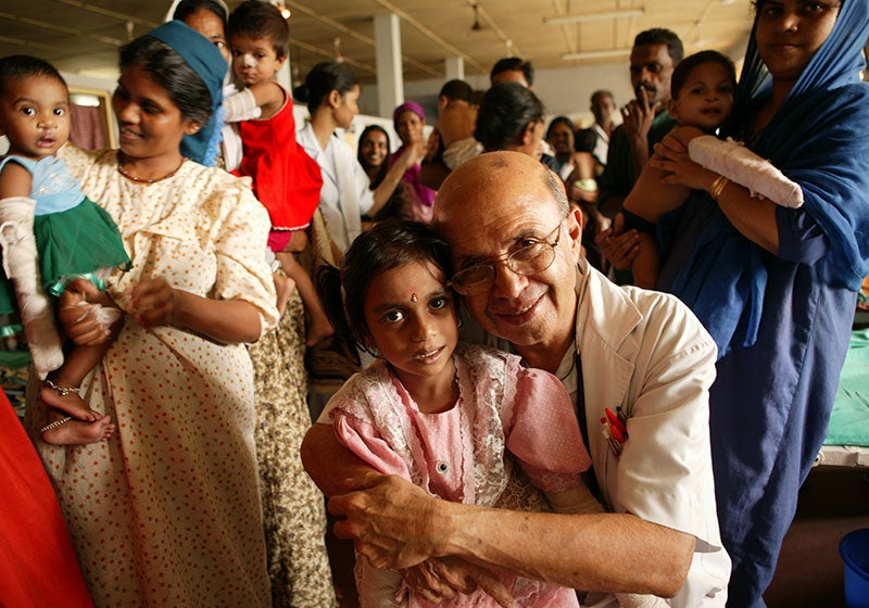 Dr. Adenwalla smiling and hugging a patient