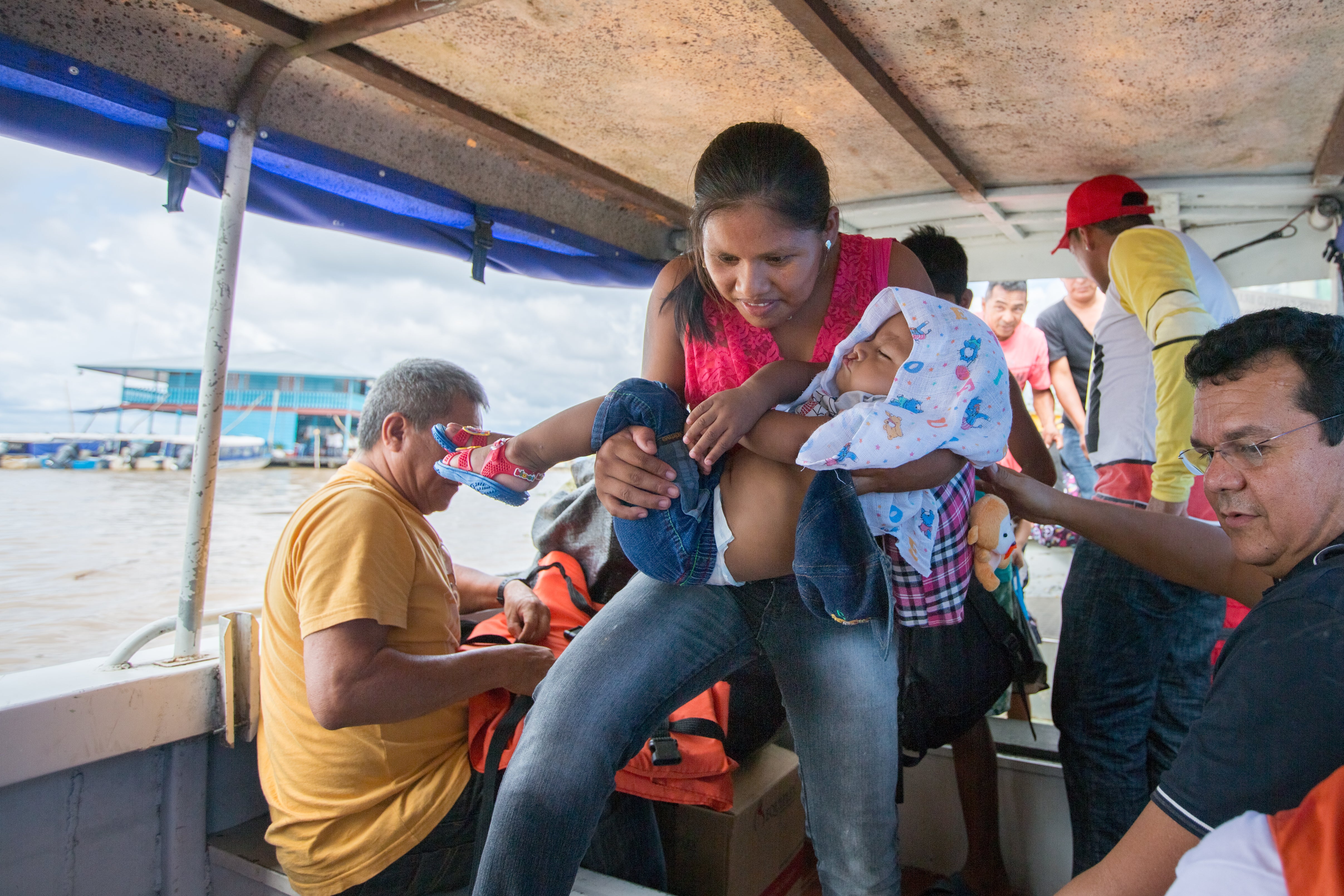 Jeane segura Kalebe em um barco para Benjamin Constant