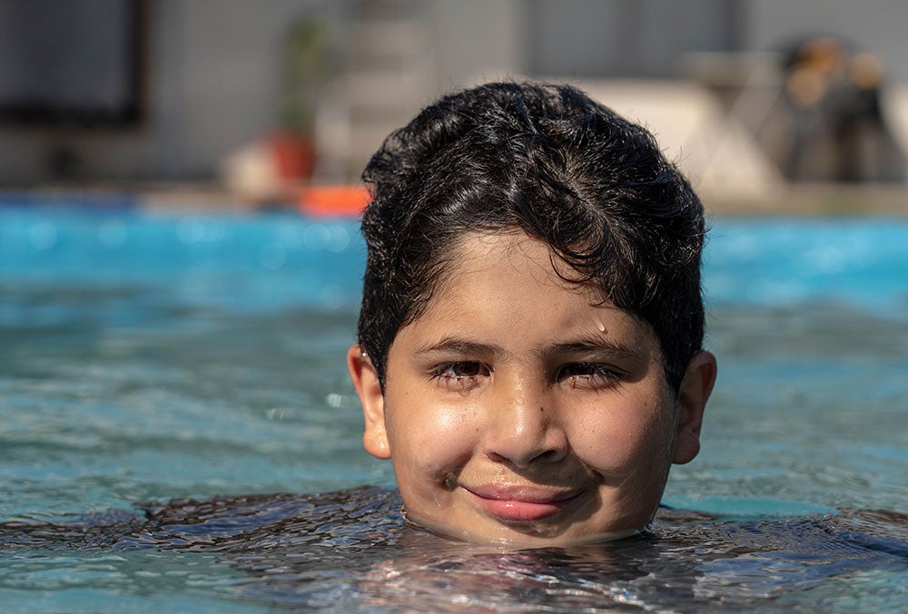 Juan smiling and swimming in a pool