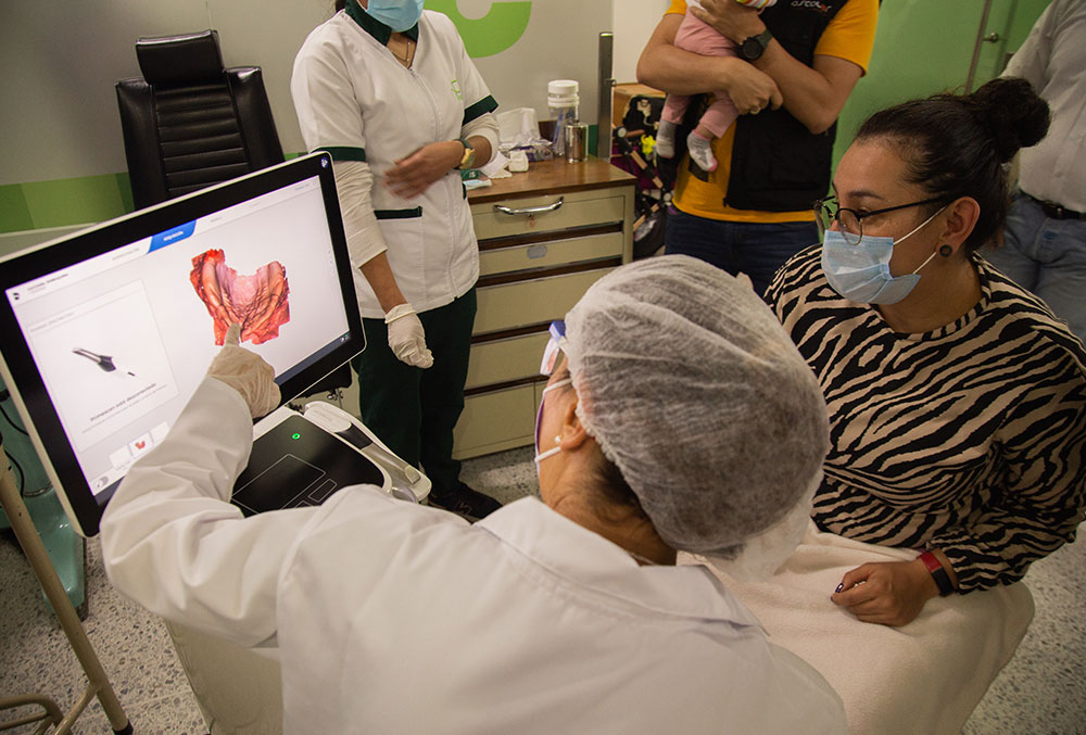 Um técnico da FISULAB analisa uma digitalização 3D do Primescan AC com a mãe de um paciente