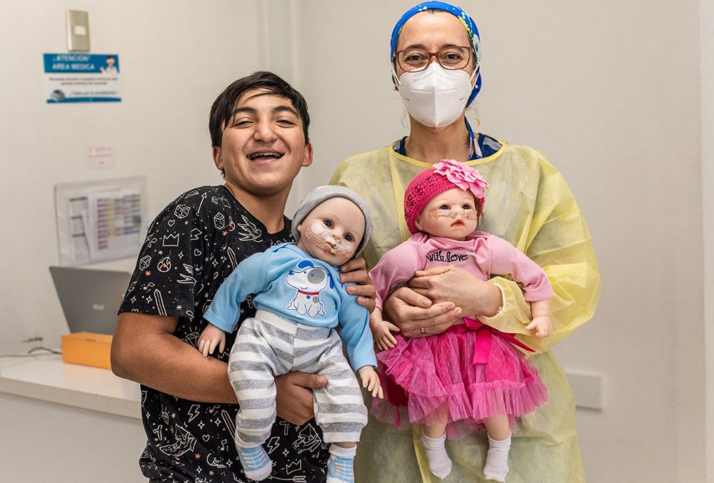 Vicente smiling and holding Smile Train cleft simulation dolls