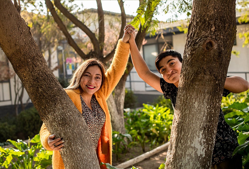 Vicente sorrindo e de mãos dadas com sua mãe Paola