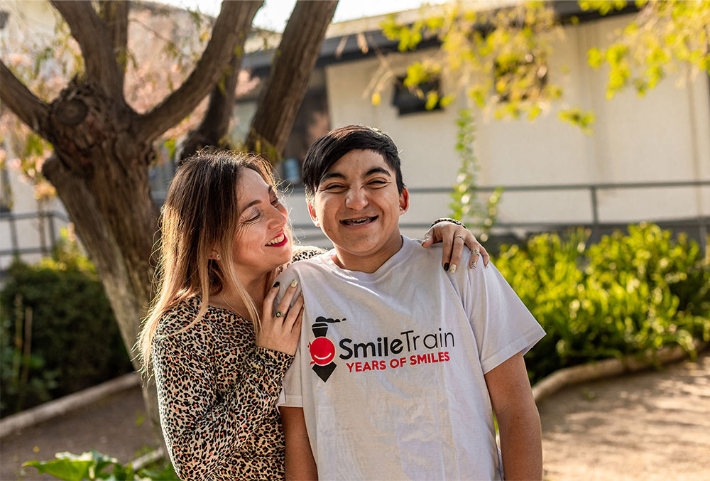 Vicente sorrindo com sua mãe paola com Smile Train tshirt