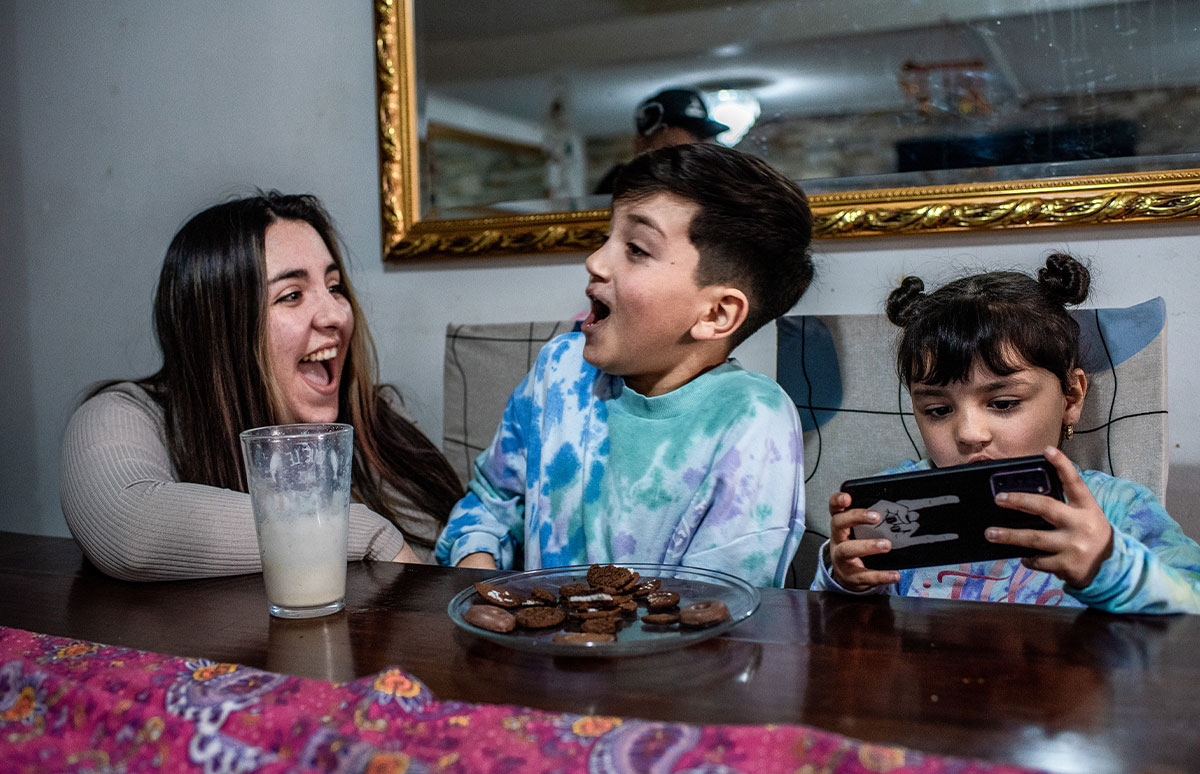 Joaquin and his mother share a laugh over cookies and milk as Amanda plays on her phone