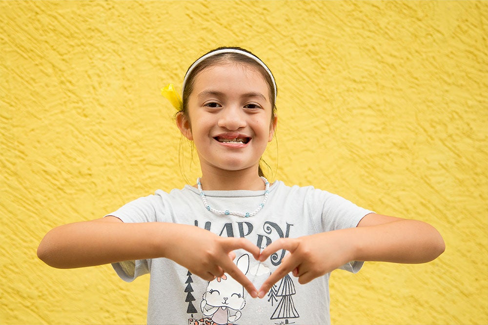 Aquetzaly smiling and signing a heart after cleft surgery