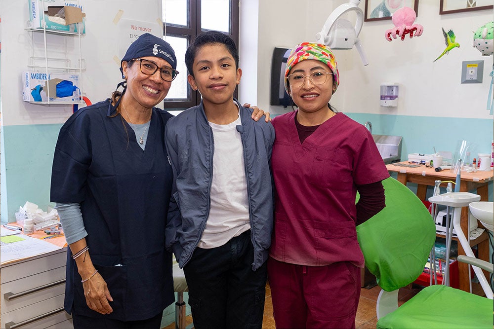 Brosly posing with her assistant and a patient