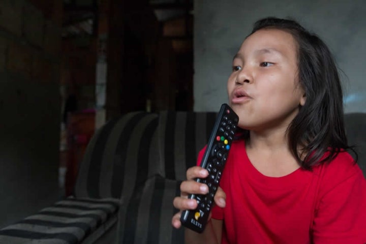 Victoria usando um controle remoto da TV como microfone