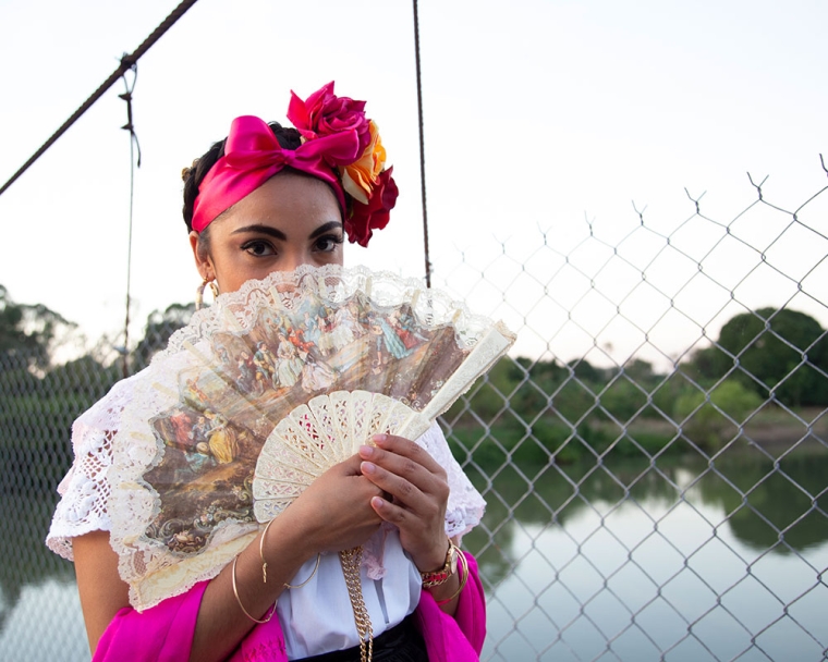 Adahara segurando um fã tradicional mexicano sobre sua boca.