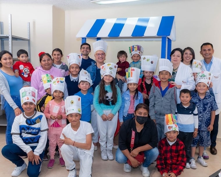 Lidia posing with a group of Smile Train patients and their parents. All kids are wearing hand-decorated chef’s hats