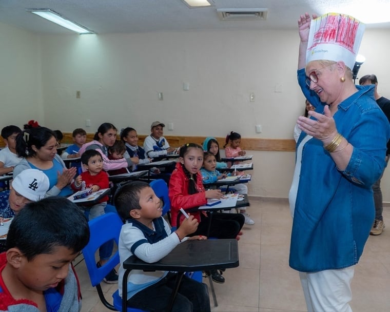 Lidia standing at the front of the room wearing a hand-decorated chef’s hat, addressing the kids